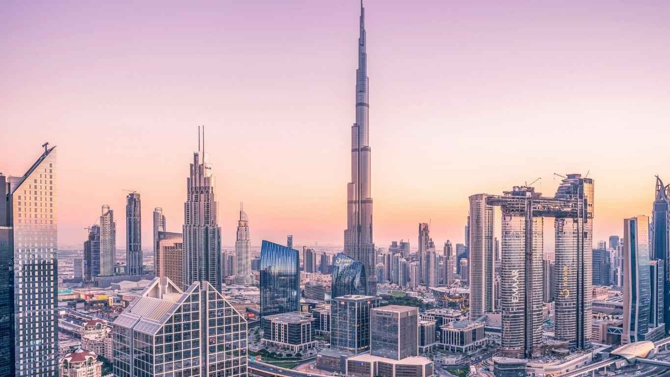 A modern international student with a laptop, smiling brightly on a vibrant campus with the iconic Dubai skyline in the background, representing the opportunity to study in Dubai.
